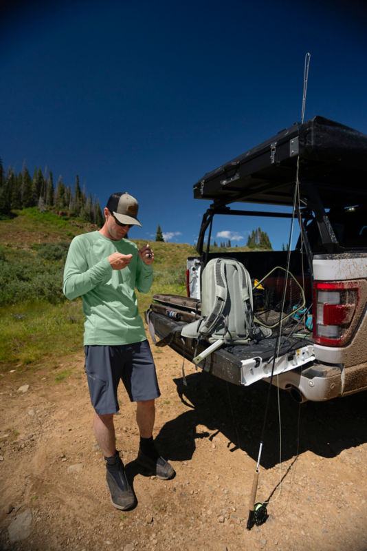 An angler checks his fishing gear in the back of his truck.