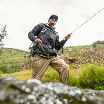 An angler wades up a rocky river.