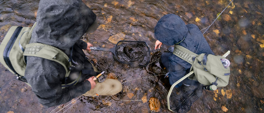 An overhead shot of a man and woman fishing in a river using a net