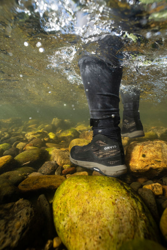 A fly angler standing on underwater rocks.