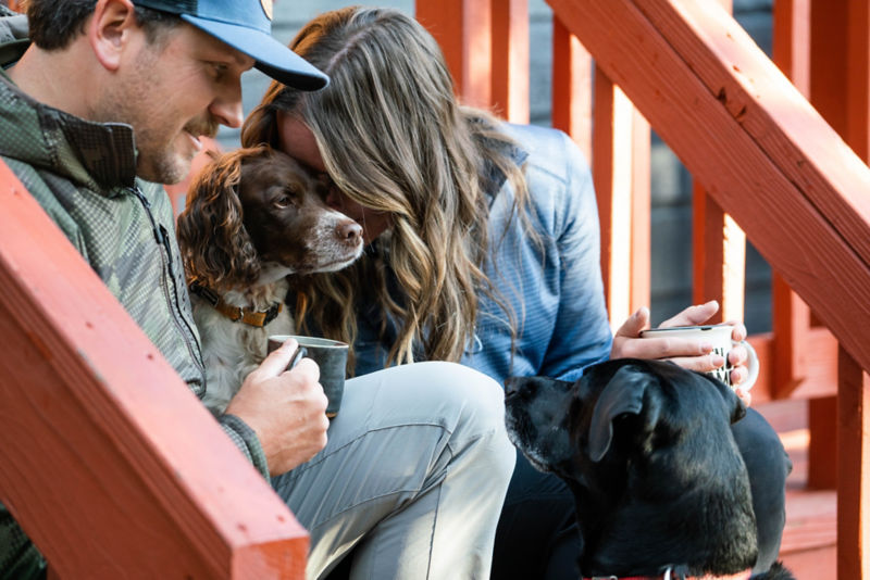 A spaniel sitting on the steps between two people.