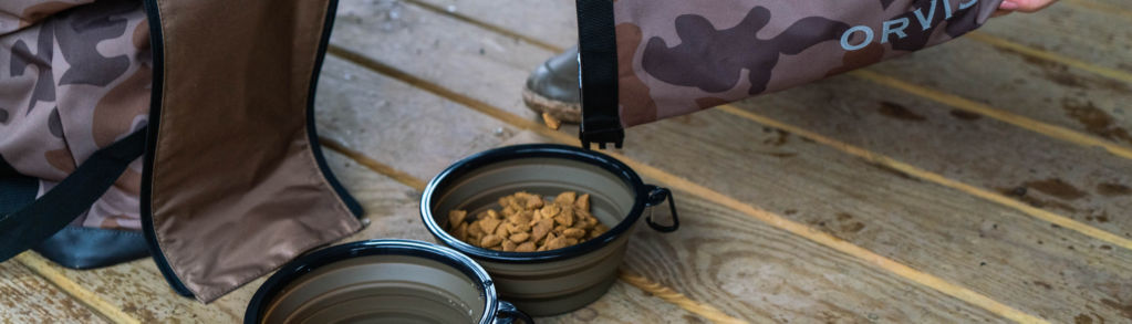 A closeup of a woman pouring food into a travel bowl from the camo chuckwagon