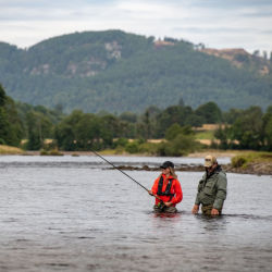 Two anglers standing hip-deep in the water in the Scottish countryside