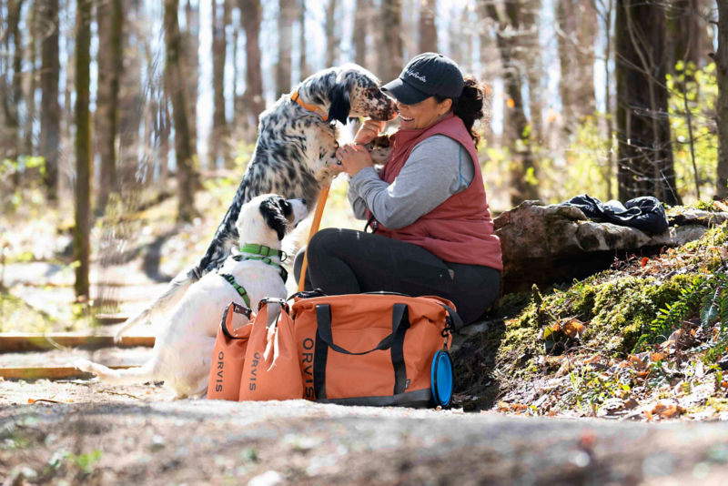 A black-freckled dog jumps up on their person while on a hike.