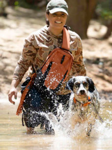 Melinda Benbow wades through a stream with her hunting dog