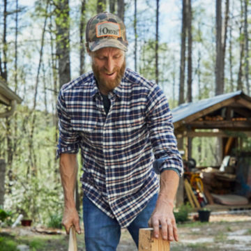 Man in Ink Mid Mountain Tech Flannel Shirt places wood to chop.