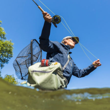Looking up from the water to a casting angler in a blue PRO jacket