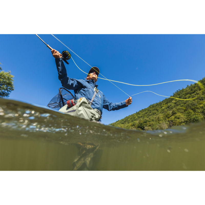 A wading angler manages their line while they cast.