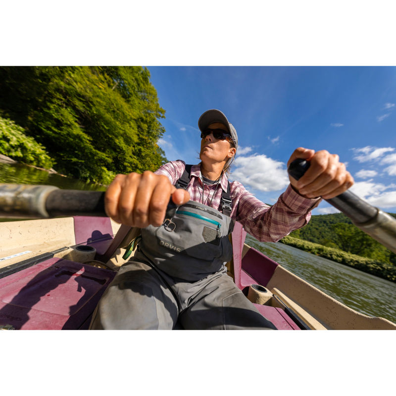 An angler rows her boat down a running river