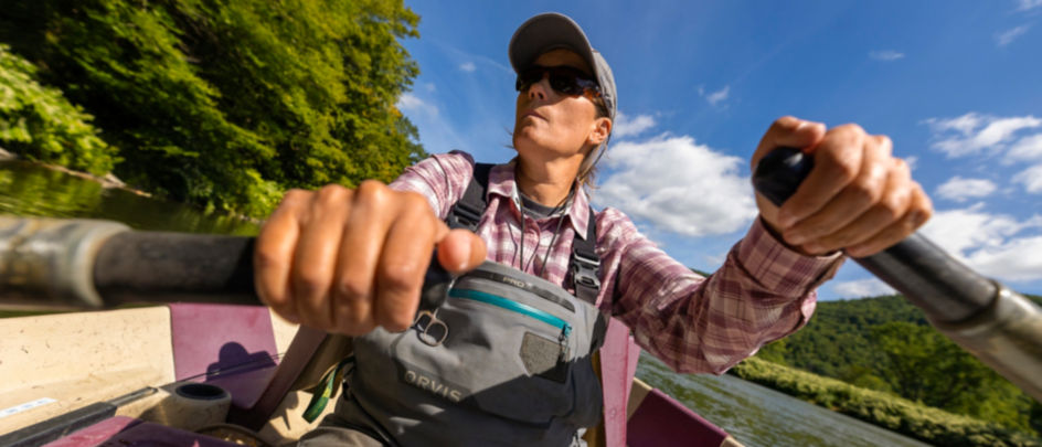 An angler rows her boat down a running river