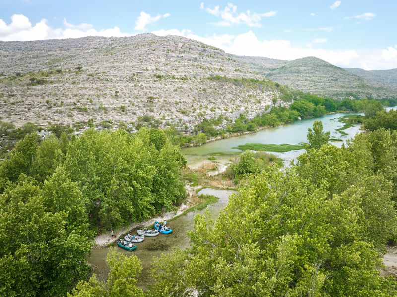 Four rafts pulled up on the stony shore of Devil's River in Texas.