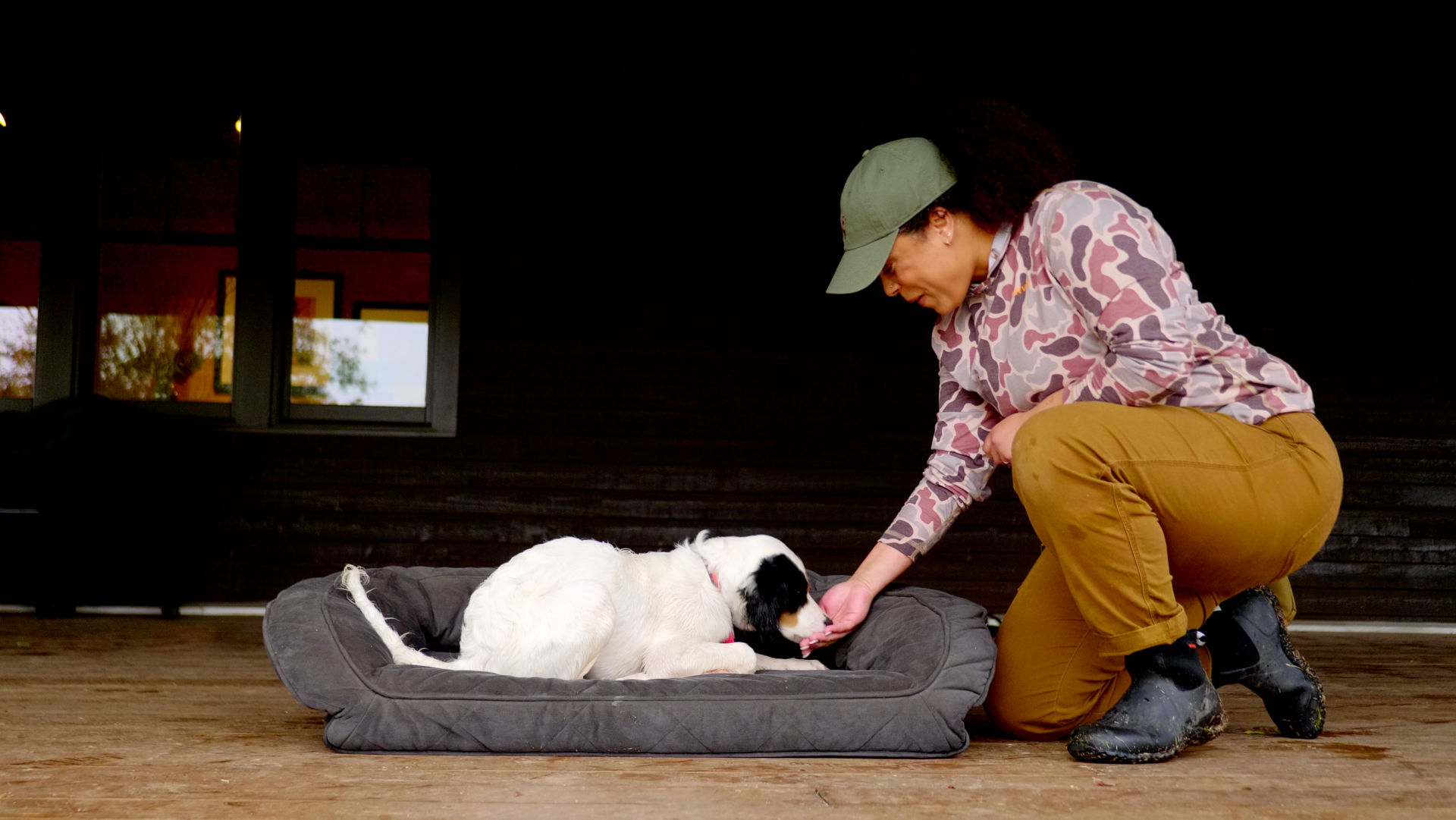 A woman showing her dog down in a dog bed