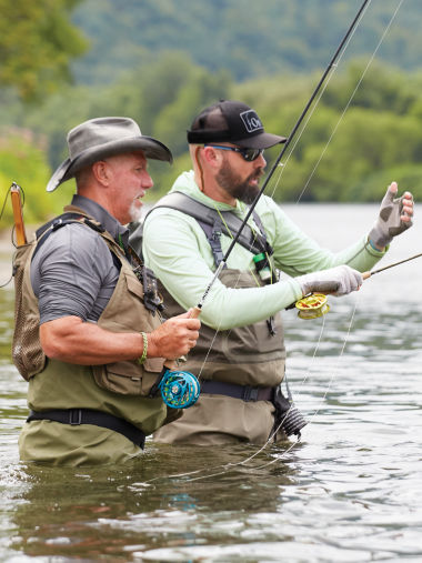 Two anglers standing hip-deep in a river fishing