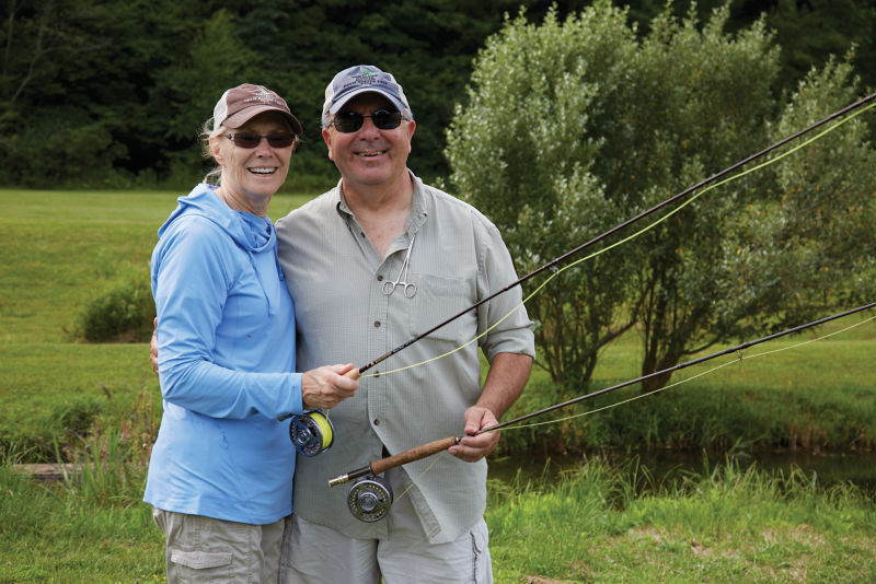 A husband and wife smile for a photo after a fun fly fishing 1001 class.