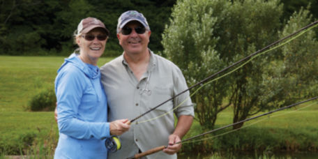 A husband and wife smile for a photo after a fun fly fishing 1001 class.