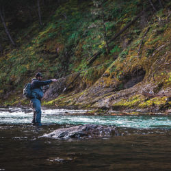 An angler lets his line drift in shallow water.