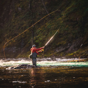 An angler casts their spey rod in the middle of a river.