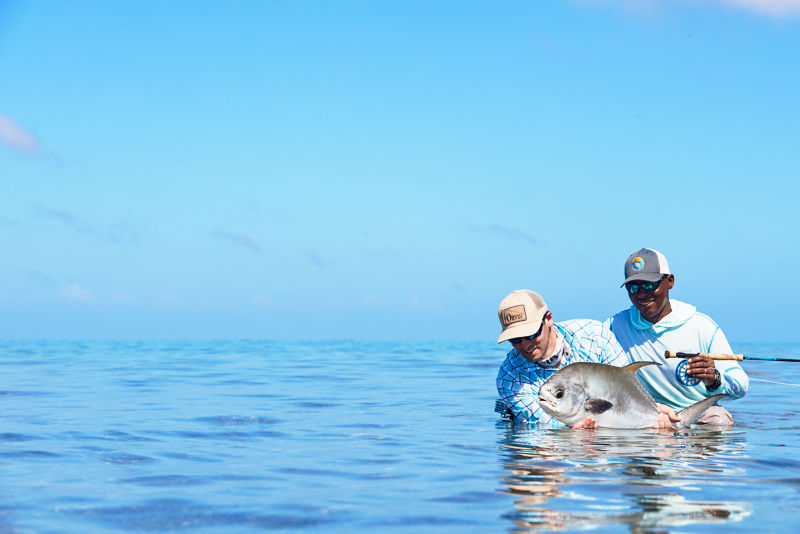 A fisherman with his guide in the ocean after catching a large permit.