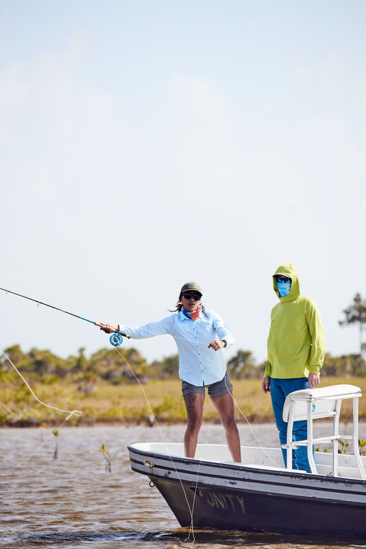 Woman fishing off boat,  looking at camera.