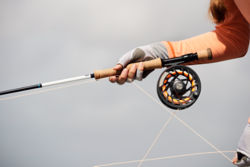 A gloved angler holds a Helios 3 rod with a large-arbor Mirage LT reel.