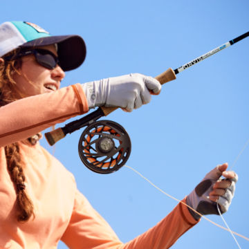 An angler wearing Orvis Sungloves throws line off her Helios 3.