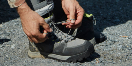 An angler ties the laces of their wading boots.