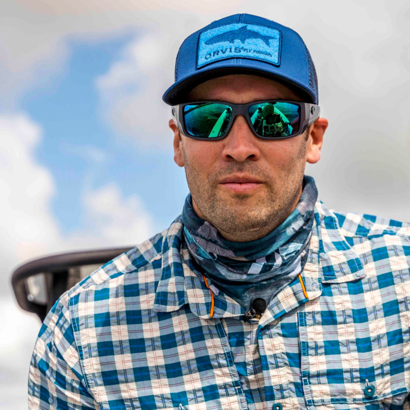 An angler with an Orvis ball cap, sunglasses, and buff.