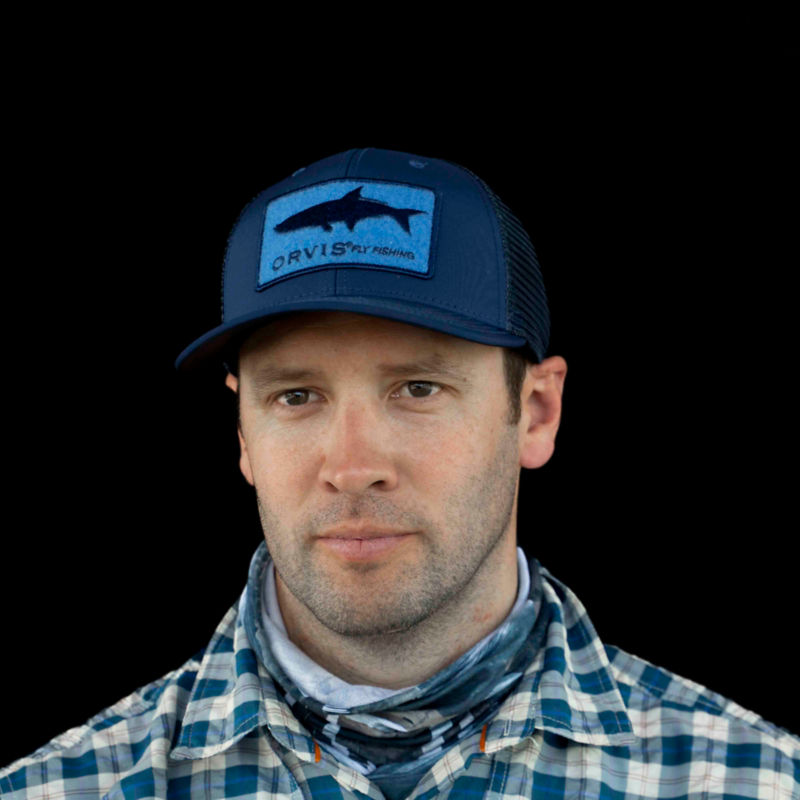 A headshot of Simon Perkins, President of Orvis, wearing a blue Orvis cap