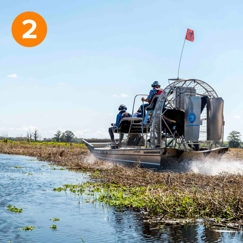 Several people in an airboat navigate the Kissimmee River