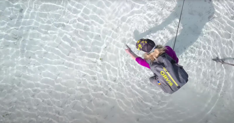 A view from above as an angler bends over to release a fish in the clear waters of the Flats.