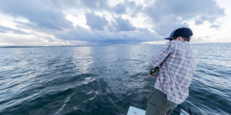 Man reeling in a fish on a boat in the ocean