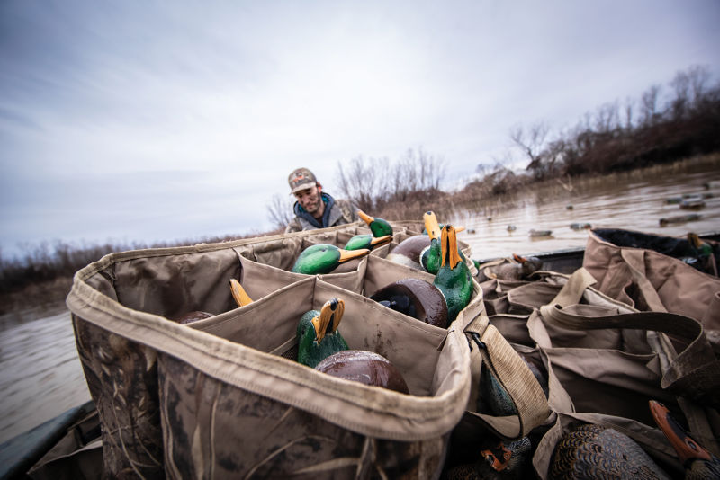 A bag of duck decoys with a hunter in camo.