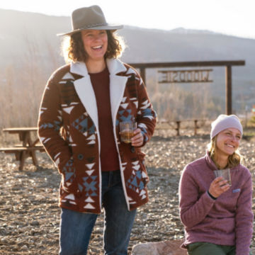Woman in Redwood Montana Morning® Fleece Jacket enjoys coffee with friends on a misty morning.