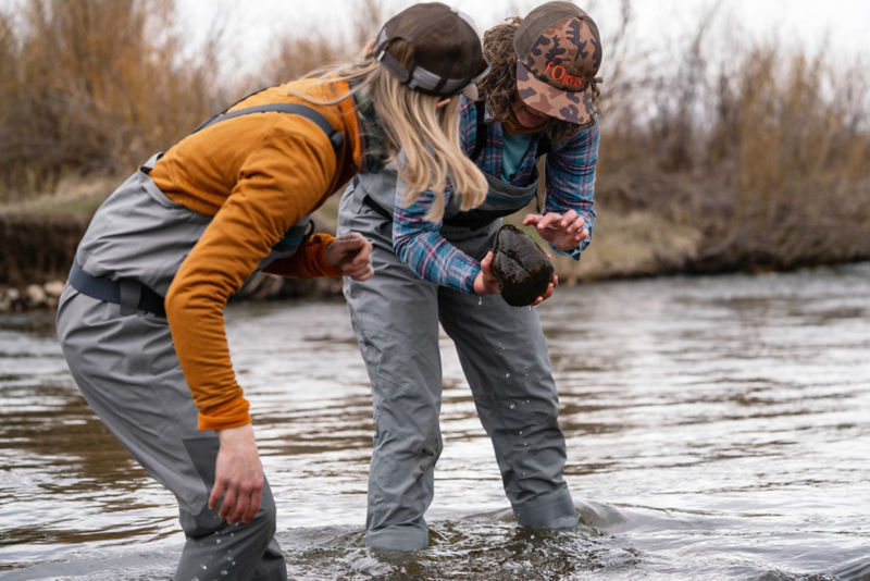Two women looking at rocks they pick out of the river.