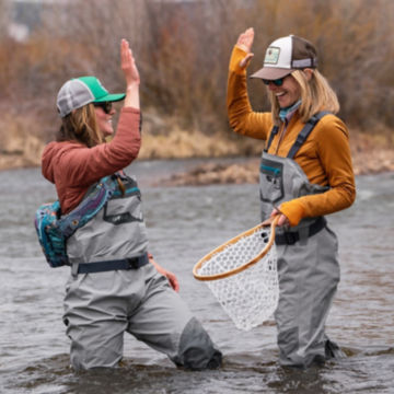 A couple of anglers in PRO waders high five mid-stream.