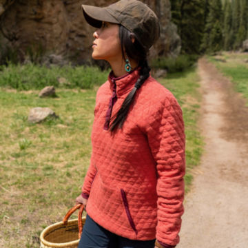 Woman in Outdoor Quilted Sweatshirt gathers foliage on a walk through a forest.