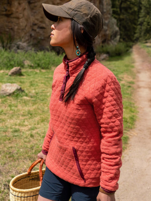 Woman in Paprika Outdoor Quilted Snap Sweatshirt Forages for woodland things.