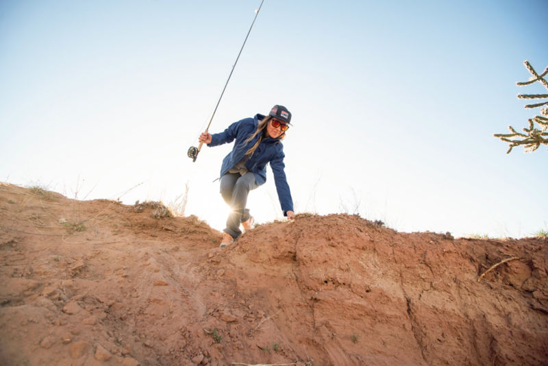 Angler hops down a rocky dune towards a river.