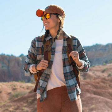 A woman in flannel backpacks through the desert