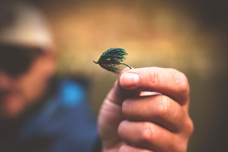 Fingers holding a fly fishing fly