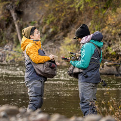 Two anglers stand face to face in the river.