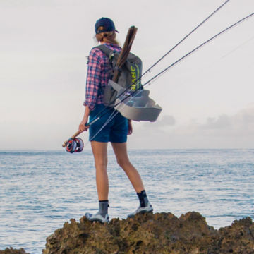 An angler looks out into the ocean, fly rod in hand.