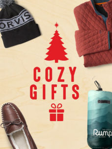 The words Cozy Gifts in red on a wood background with a few gifts .