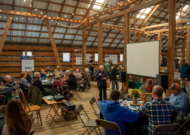 A group of people gathered inside a lodge for a corporate event.