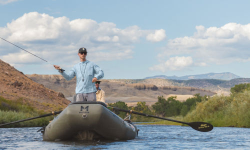 An angler stands in a raft casting his Helios Fly Rod.