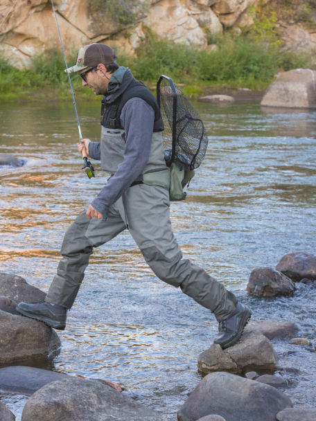 Anglers steps on rocks in a river with the PRO LT Wading Boots and PRO LT Waders