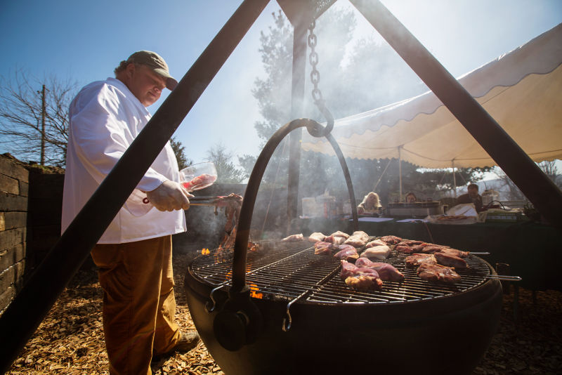 A chef demonstrating cooking game with an outdoor cauldron.