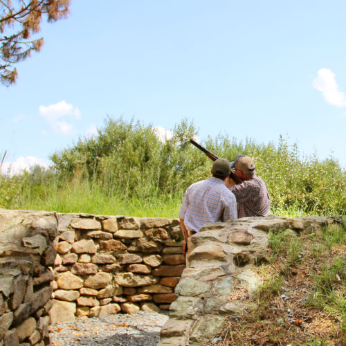 A student and an instructor behind a stone wall practicing their shot