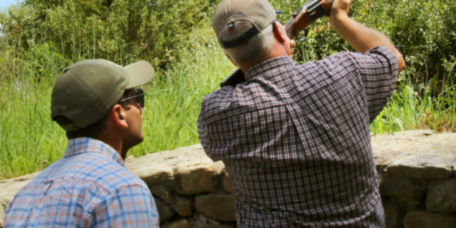 An instructor giving shooting instructions to a wingshooter.