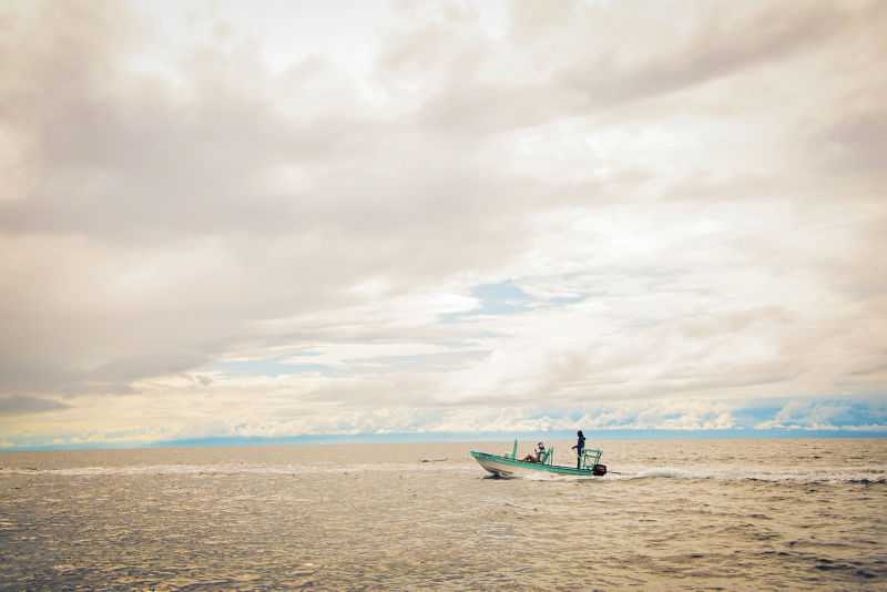 Three people in a running boat in tropical waters. 